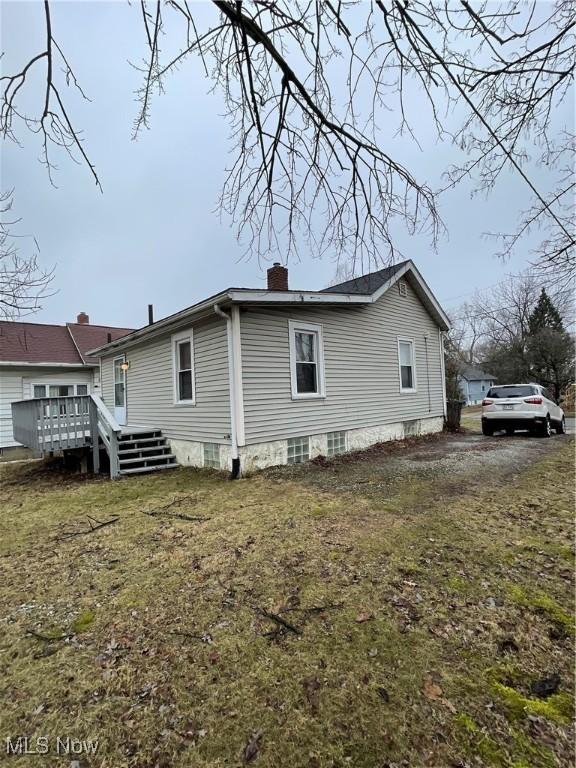 view of side of home with a wooden deck and a chimney