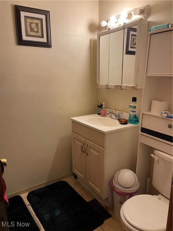 half bathroom with vanity, toilet, and baseboards