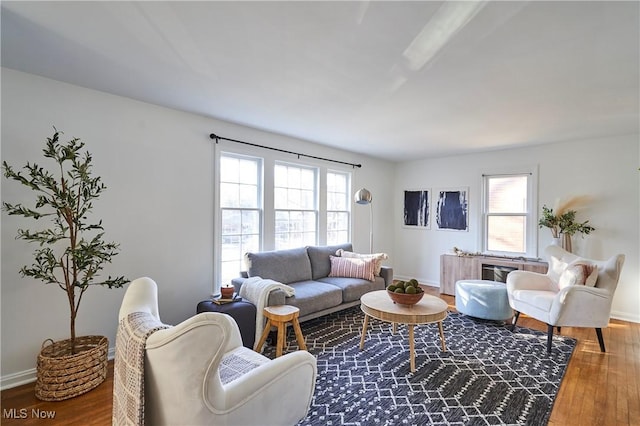 living area with baseboards, a healthy amount of sunlight, and wood finished floors