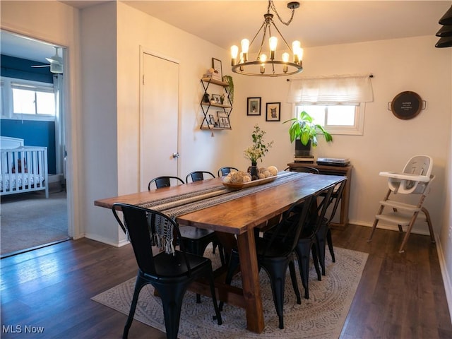 dining space with dark wood finished floors, a notable chandelier, and baseboards