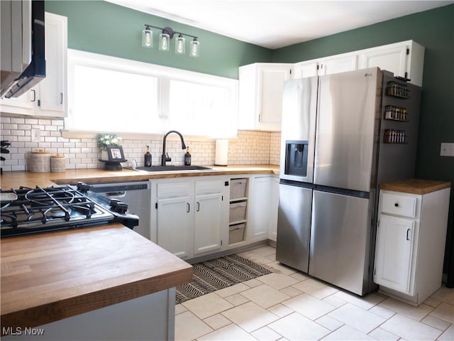 kitchen featuring a sink, decorative backsplash, white cabinets, stainless steel refrigerator with ice dispenser, and wood counters