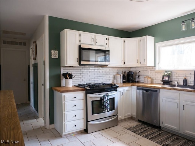 kitchen with visible vents, backsplash, white cabinets, stainless steel appliances, and a sink