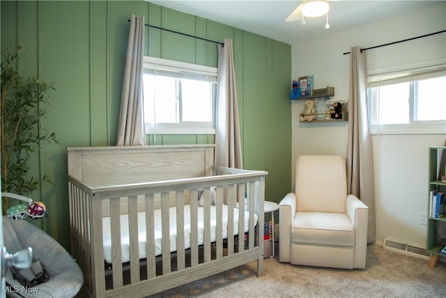 bedroom featuring carpet flooring, a crib, and visible vents