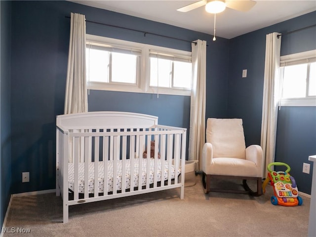 bedroom with carpet flooring, a crib, and a ceiling fan