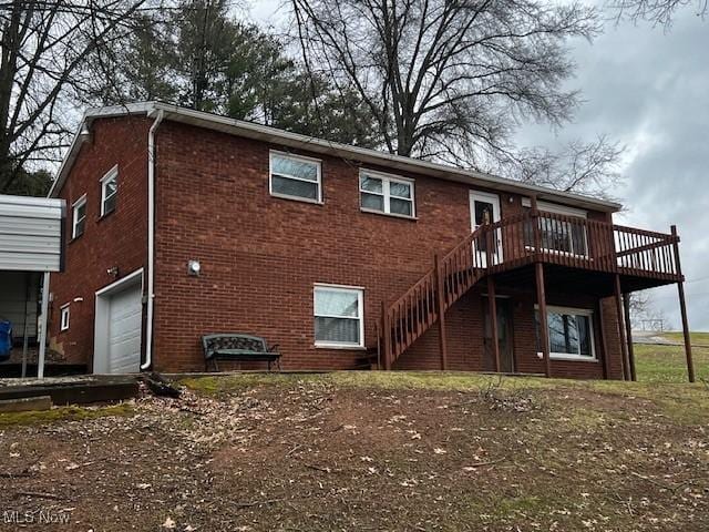 rear view of house with stairs, a garage, brick siding, and a wooden deck