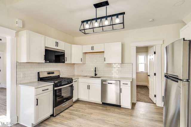 kitchen with light countertops, white cabinets, appliances with stainless steel finishes, and a sink