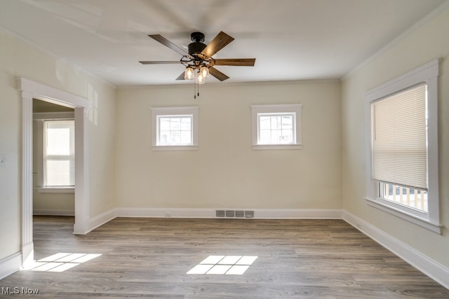 unfurnished room featuring visible vents, crown molding, baseboards, and wood finished floors