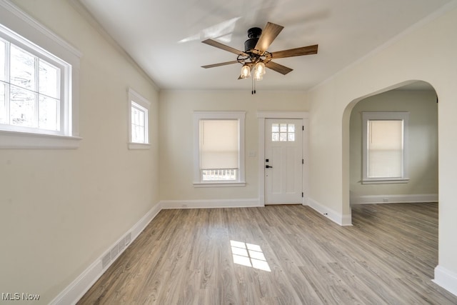 foyer entrance featuring visible vents, baseboards, ornamental molding, and light wood finished floors