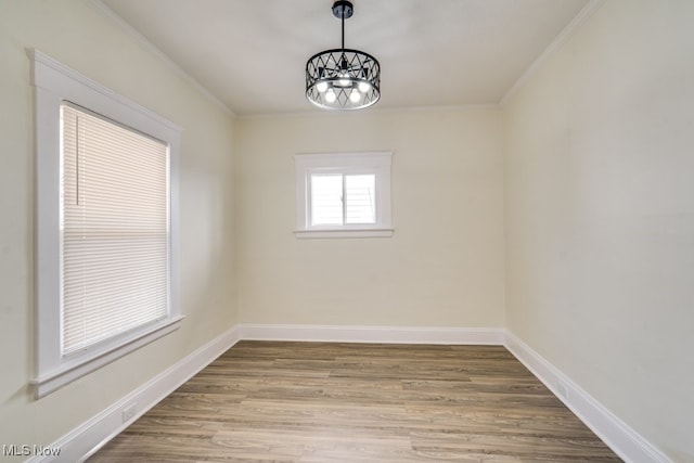 spare room with crown molding, wood finished floors, and baseboards