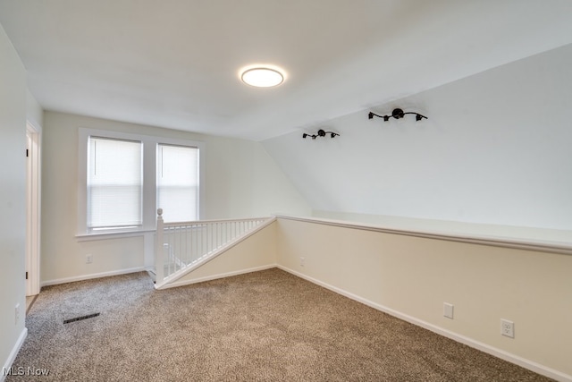 spare room with visible vents, carpet flooring, baseboards, and lofted ceiling