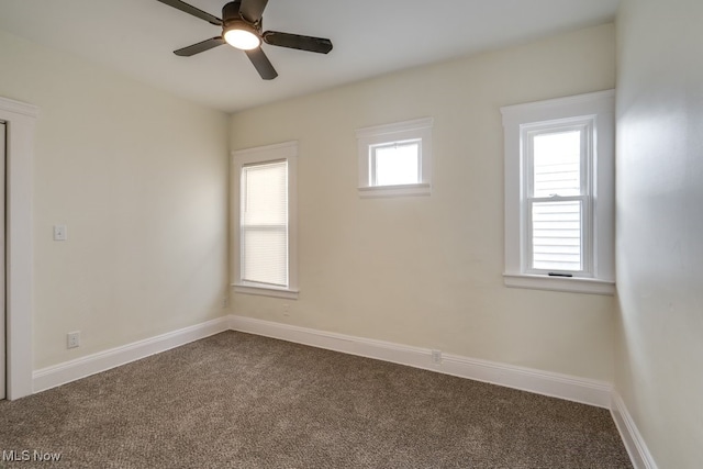 empty room with plenty of natural light, dark carpet, and baseboards