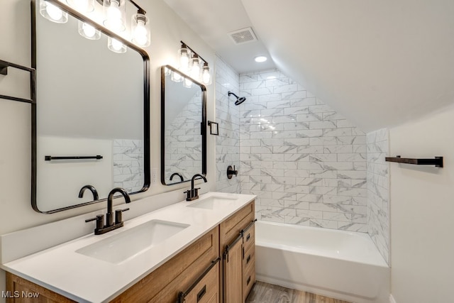 bathroom featuring a sink, visible vents, lofted ceiling, and washtub / shower combination