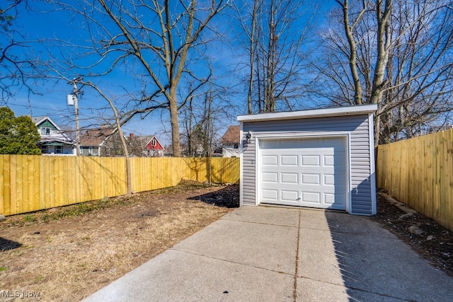 detached garage featuring driveway and fence