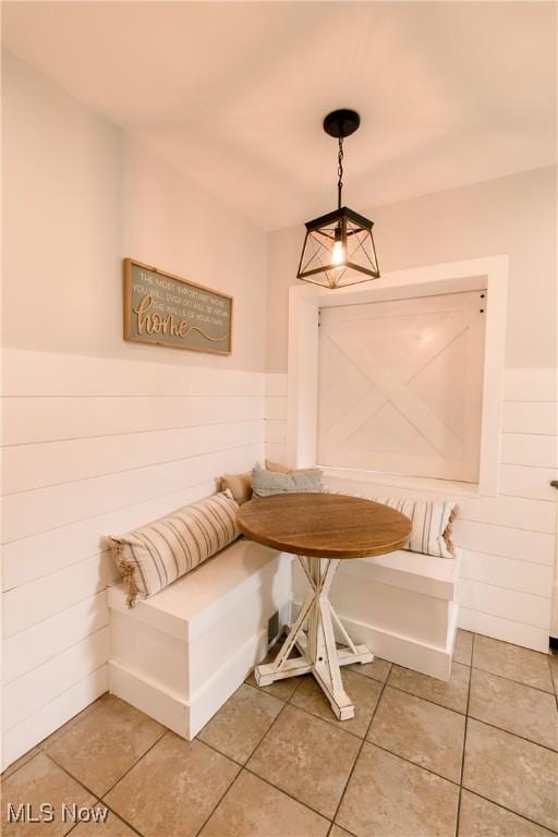 unfurnished dining area with breakfast area, a wainscoted wall, and light tile patterned flooring