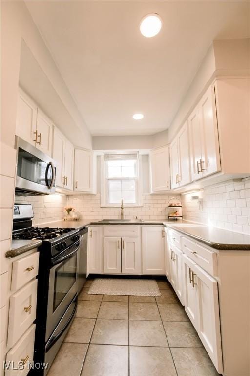 kitchen featuring backsplash, appliances with stainless steel finishes, white cabinets, and a sink