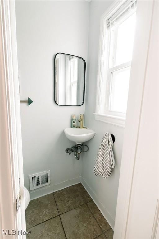 bathroom with visible vents, baseboards, toilet, tile patterned floors, and a sink