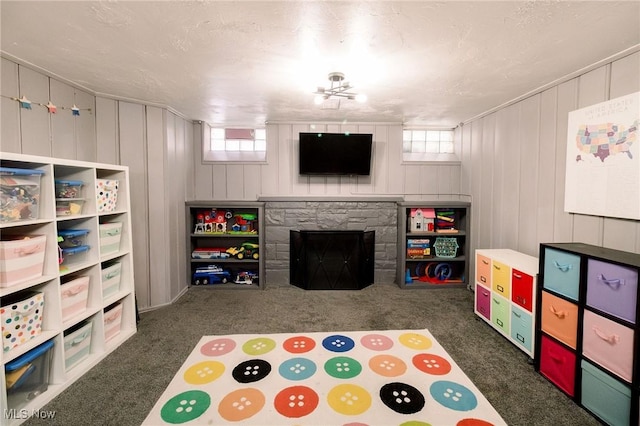 recreation room featuring a stone fireplace and carpet floors