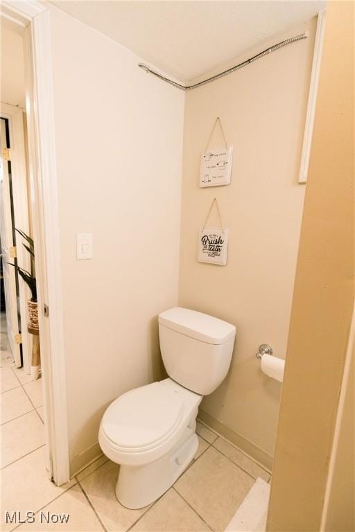 bathroom with tile patterned flooring, toilet, and baseboards