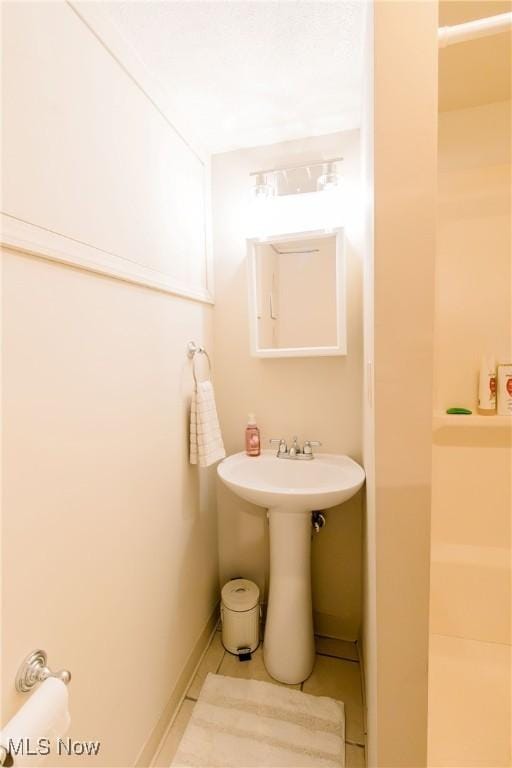 full bath with tile patterned flooring, baseboards, and a sink