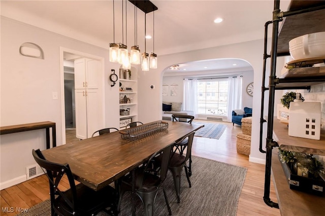 dining room featuring visible vents, baseboards, recessed lighting, light wood-style floors, and arched walkways