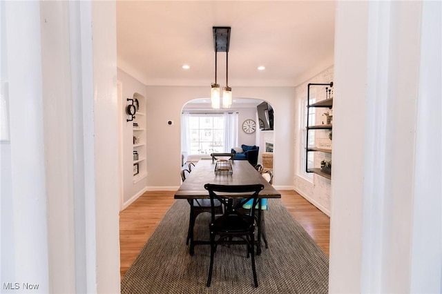 dining space with baseboards, built in features, recessed lighting, light wood-style floors, and arched walkways