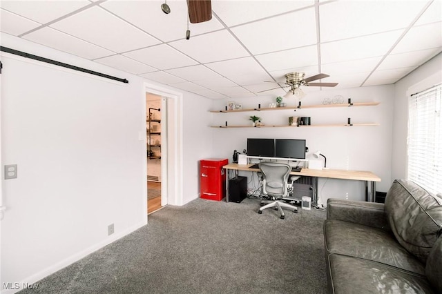 carpeted home office with baseboards, a drop ceiling, and ceiling fan