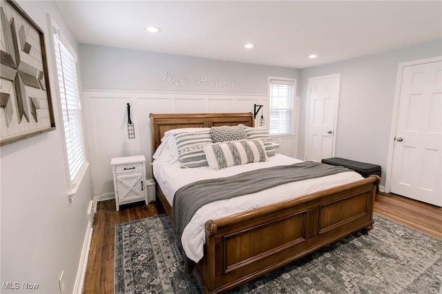 bedroom with dark wood finished floors, recessed lighting, and wainscoting