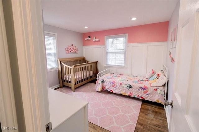 bedroom with recessed lighting, a wainscoted wall, multiple windows, and wood finished floors