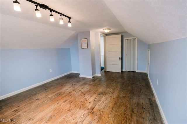 additional living space featuring a textured ceiling, lofted ceiling, baseboards, and wood finished floors