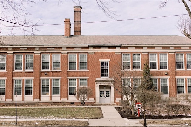 view of front of home with brick siding and a chimney