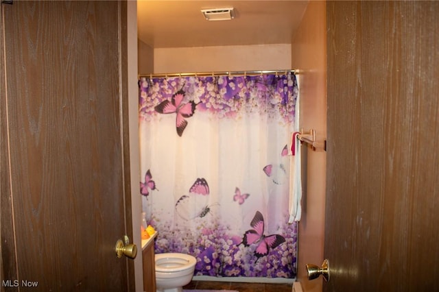 full bath featuring a shower with shower curtain, toilet, and visible vents