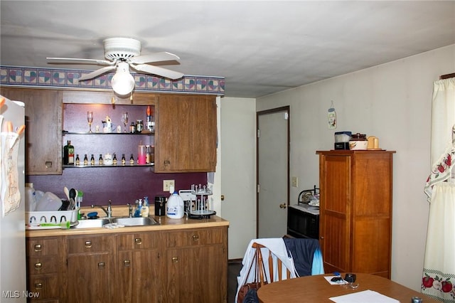 kitchen with light countertops, brown cabinetry, a ceiling fan, and a sink