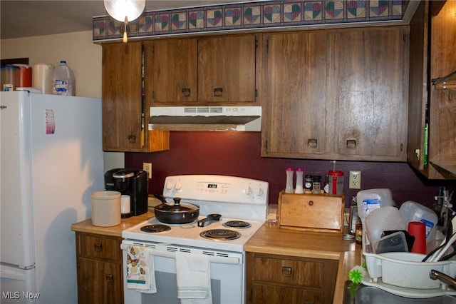 kitchen with under cabinet range hood, brown cabinets, white appliances, and light countertops