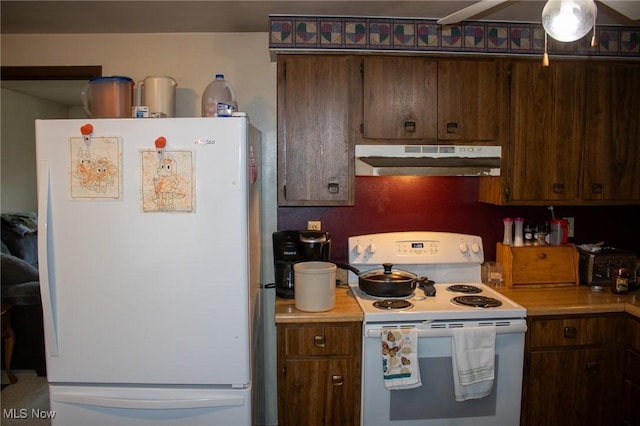 kitchen with under cabinet range hood, white appliances, and light countertops