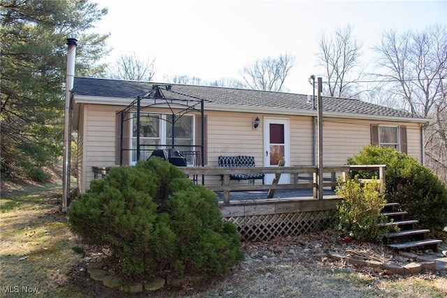 rear view of house featuring a wooden deck and roof with shingles