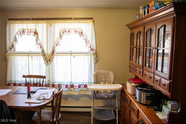 dining room with a wealth of natural light, a baseboard heating unit, and wood finished floors