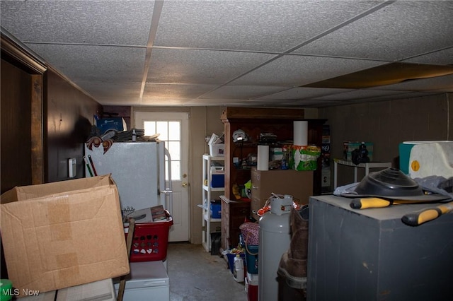 below grade area with a paneled ceiling and freestanding refrigerator