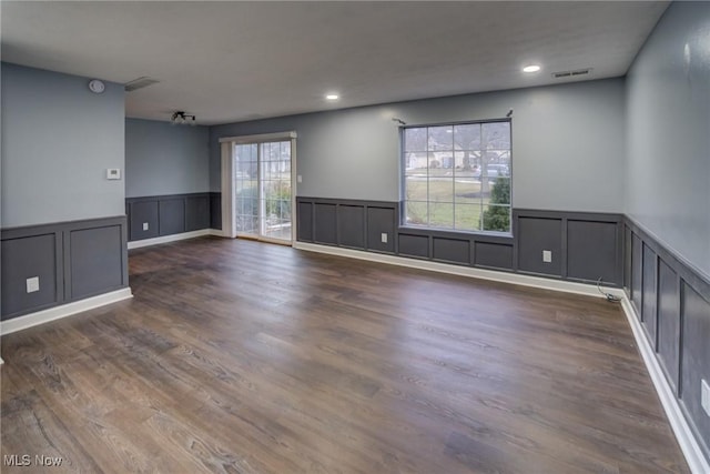 spare room featuring visible vents, a wainscoted wall, and wood finished floors