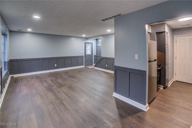 unfurnished room with dark wood finished floors, visible vents, and wainscoting