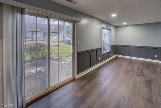 empty room with recessed lighting, a wainscoted wall, and dark wood-style floors