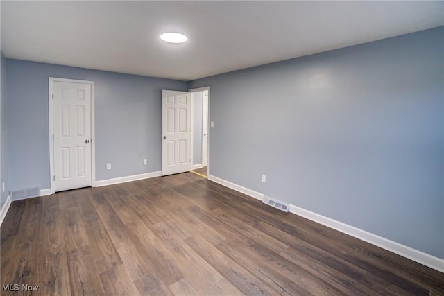 spare room featuring visible vents, baseboards, and wood finished floors