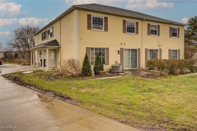 view of front facade with driveway, a front yard, and central AC