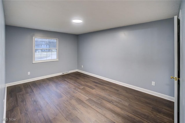 spare room with visible vents, baseboards, and dark wood-style flooring