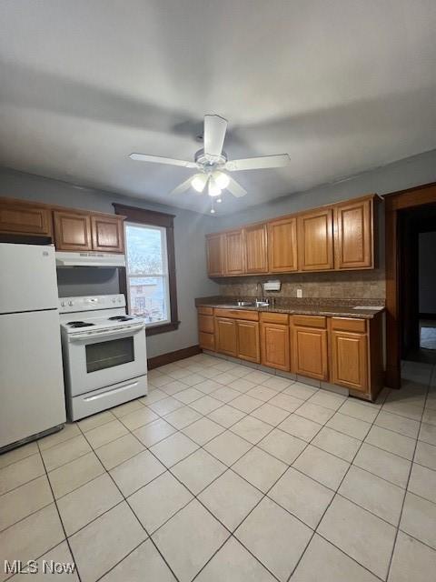 kitchen featuring backsplash, brown cabinets, white appliances, a ceiling fan, and a sink