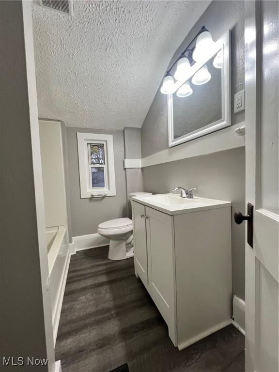 bathroom featuring visible vents, toilet, a textured ceiling, wood finished floors, and vanity