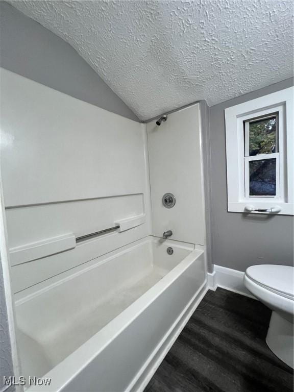 bathroom with toilet, lofted ceiling, a textured ceiling, wood finished floors, and baseboards