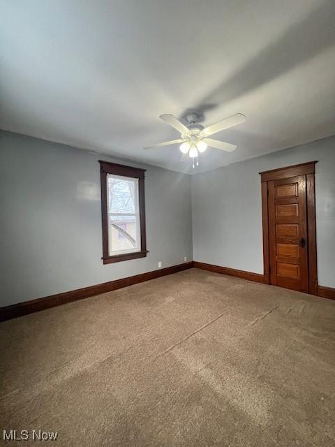 spare room featuring light colored carpet, baseboards, and ceiling fan