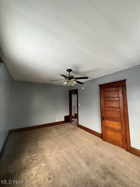 empty room with baseboards, light colored carpet, and ceiling fan