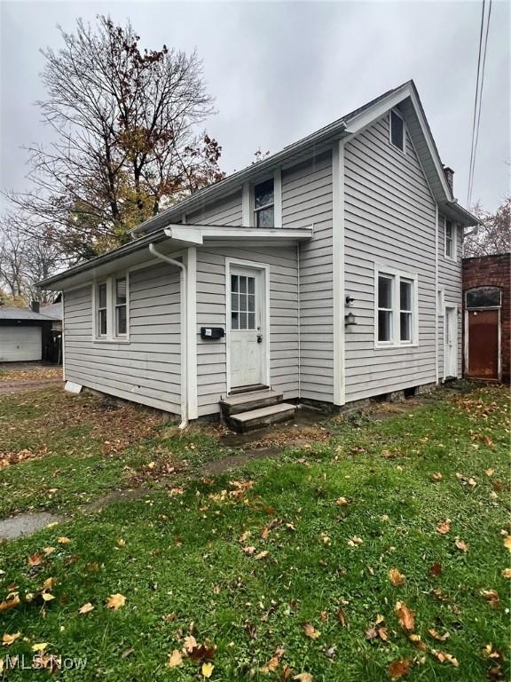 back of house featuring entry steps and a lawn