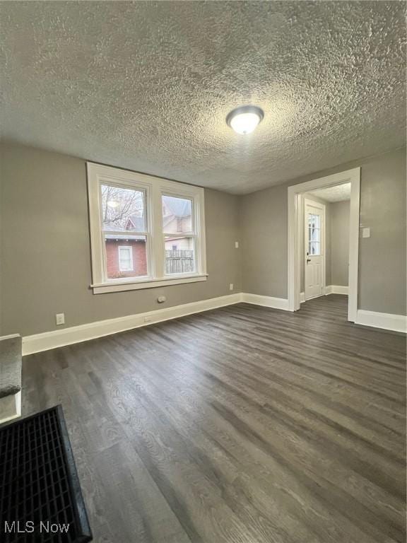 empty room with baseboards, dark wood-type flooring, and a textured ceiling